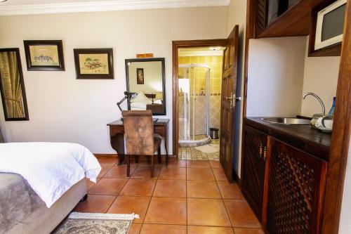 a bedroom with a bed and a sink and a bathroom at Royl Court Guesthouse in Kimberley