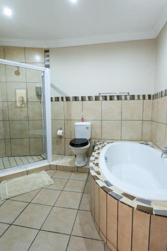 a bathroom with a bath tub and a toilet at Royl Court Guesthouse in Kimberley