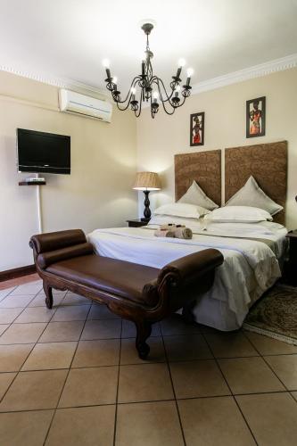 a bedroom with a large bed and a chandelier at Royl Court Guesthouse in Kimberley