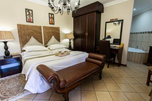a bedroom with a bed and a desk and a mirror at Royl Court Guesthouse in Kimberley