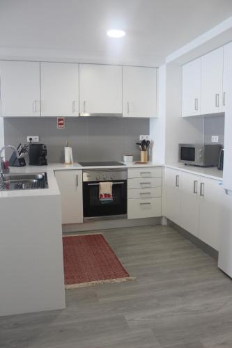 a kitchen with white cabinets and a stove top oven at Happy House in Ponta Delgada