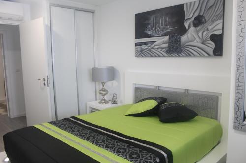 Un dormitorio con una cama verde con una pintura en la pared en Happy House, en Ponta Delgada