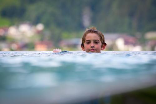 a young boy is swimming in the water at Alpin Family Resort Seetal in Kaltenbach