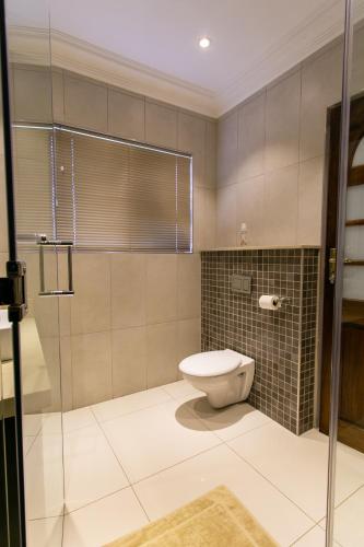 a bathroom with a toilet and a glass shower at Royl Court Guesthouse in Kimberley