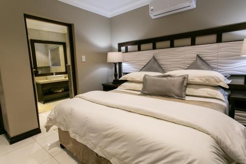 a bedroom with a large bed and a mirror at Royl Court Guesthouse in Kimberley