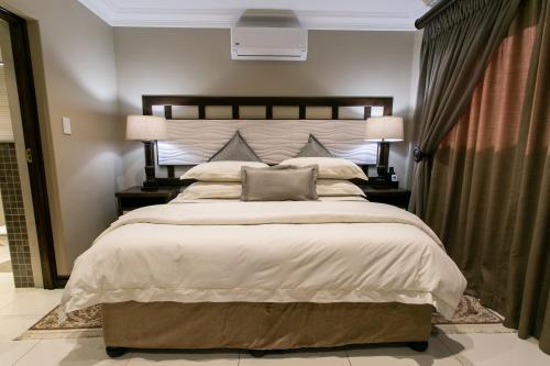 a bedroom with a large bed with two lamps at Royl Court Guesthouse in Kimberley