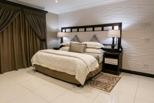 a bedroom with a large bed and a table with a lamp at Royl Court Guesthouse in Kimberley