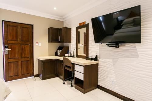 a kitchen with a flat screen tv on a wall at Royl Court Guesthouse in Kimberley
