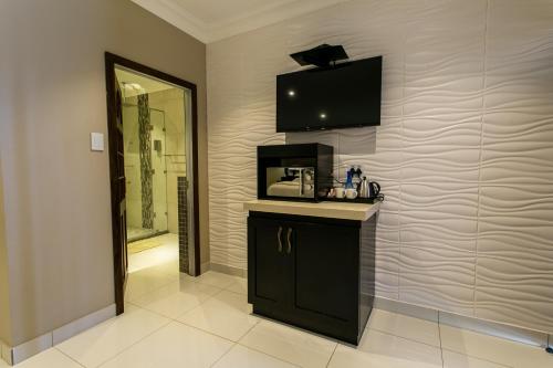 a bathroom with a counter and a television on the wall at Royl Court Guesthouse in Kimberley