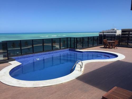 una piscina en la parte superior de un edificio con el océano en Apartamento Port Ville Mar Azul, en Maceió