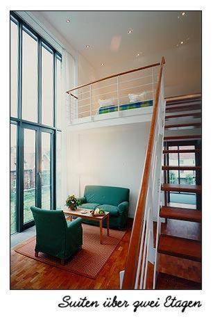 a living room with a staircase and a green couch at Hotel Oberschwaebischer Hof in Schwendi