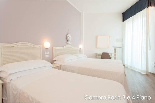 two beds in a hotel room with white sheets at Hotel Roxy & Beach in Cesenatico