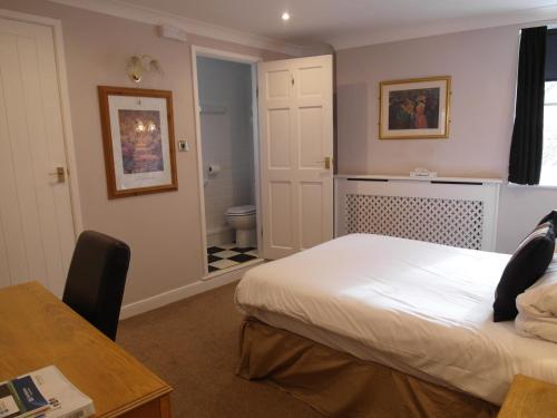 a bedroom with a bed and a bathroom with a toilet at Best Western The George Hotel, Swaffham in Swaffham