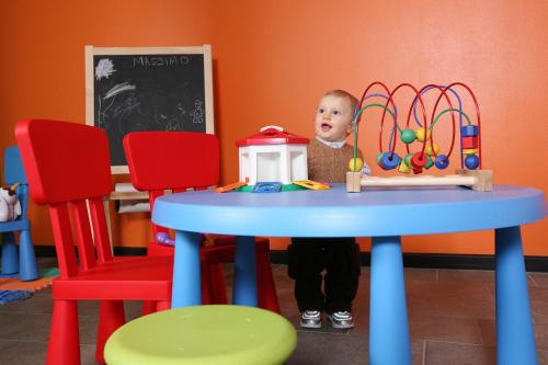 
a small child sitting at a table with a toy at Miramonti Park Hotel in Bormio
