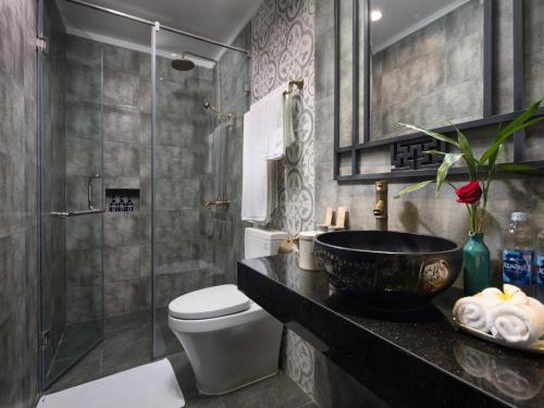 a bathroom with a sink and a toilet and a shower at The Blue Alcove Hotel in Hoi An