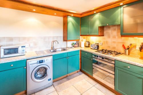 een keuken met groene kasten en een wasmachine en droger bij Mycosy on the river in Aberdeen