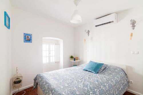 ein Schlafzimmer mit einem Bett mit einem blauen Kissen darauf in der Unterkunft Poet's house in historic center in Évora