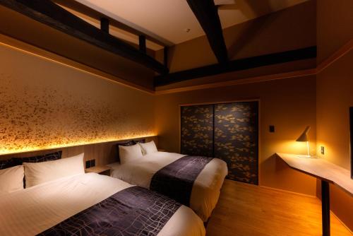 2 Betten in einem Hotelzimmer mit Beleuchtung in der Unterkunft Tsumugi Sanjusangendo in Kyoto