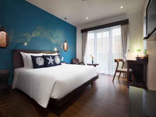 a bedroom with a large bed and a blue wall at The Blue Alcove Hotel in Hoi An
