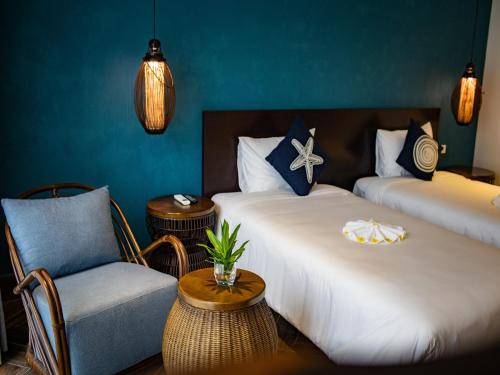 um quarto de hotel com duas camas e uma cadeira em The Blue Alcove Hotel em Hoi An