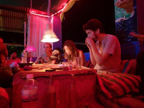 um grupo de pessoas sentadas à volta de uma mesa numa sala em Vicky's Home Stay Hampi em Hampi