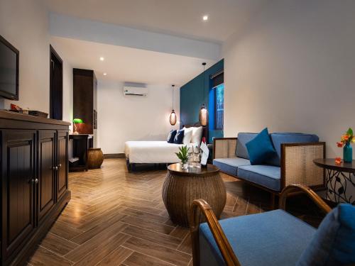 a hotel room with a bed and a couch at The Blue Alcove Hotel in Hoi An