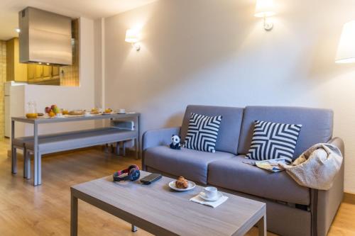 a living room with a blue couch and a table at Pierre & Vacances Andorra Alba in El Tarter