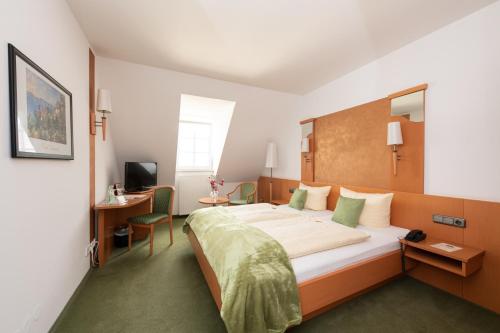 ein Hotelzimmer mit einem großen Bett und einem Schreibtisch in der Unterkunft Hotel Bitburger Hof in Bitburg