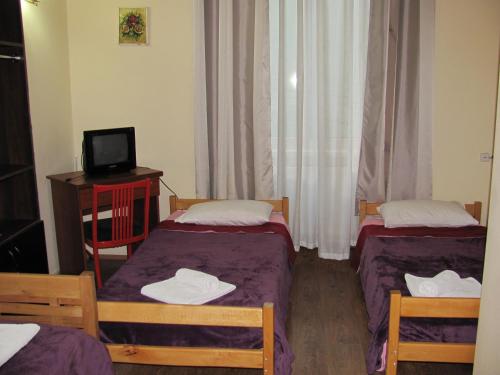 a small room with two beds and a television at Lucky Travelers Room in Tbilisi City