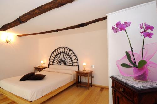 1 dormitorio con 1 cama y un jarrón con flores púrpuras en Residenza Luce en Amalfi