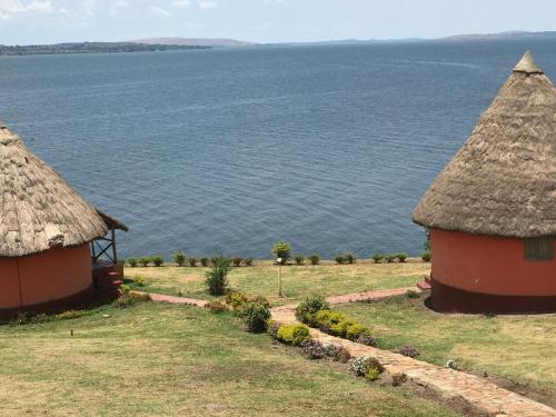 two huts with a view of the water at Samuka Island Retreat in Jinja