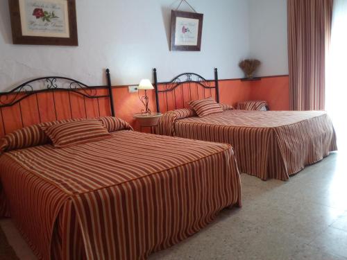 カサジャ・デ・ラ・シエラにあるBarrio Nuevoのオレンジ色の壁のホテルルーム内のベッド2台