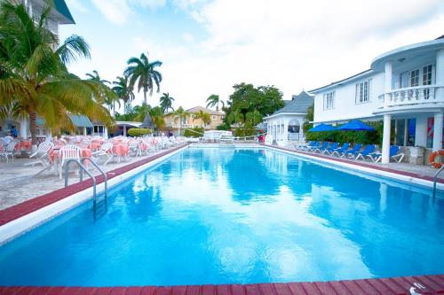 a large blue swimming pool with chairs and palm trees at SeaGarden Beach Resort - All Inclusive in Montego Bay
