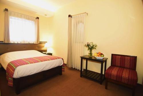 een slaapkamer met een bed, een tafel en een stoel bij Tampu Hotel in Cuzco
