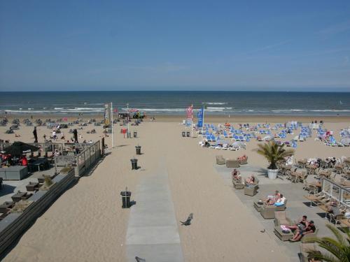a beach with chairs and people on the sand and the ocean at Dar Cho Apartment in Zandvoort