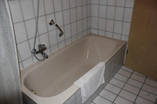 uma banheira branca numa casa de banho com azulejos brancos em Ferienwohnungen-Goldbach Erdgeschoss em Regensburg