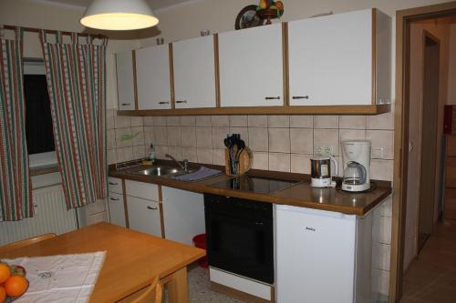 uma pequena cozinha com armários brancos e um lavatório em Ferienwohnungen-Goldbach Erdgeschoss em Regensburg