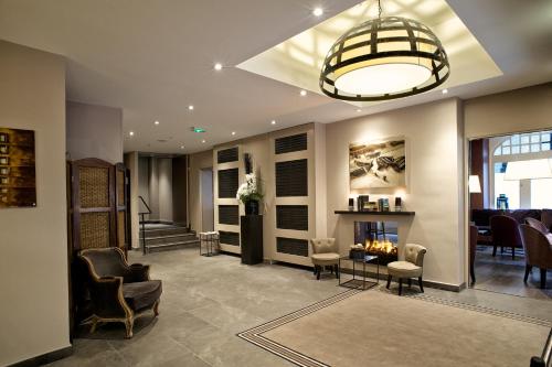 a lobby with a waiting area with chairs and a fireplace at La Maison des Armateurs in Saint Malo