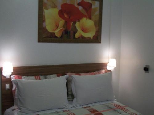 a bedroom with two pillows and a painting on the wall at Hospedagem Da Laranjeira Gramado in Gramado