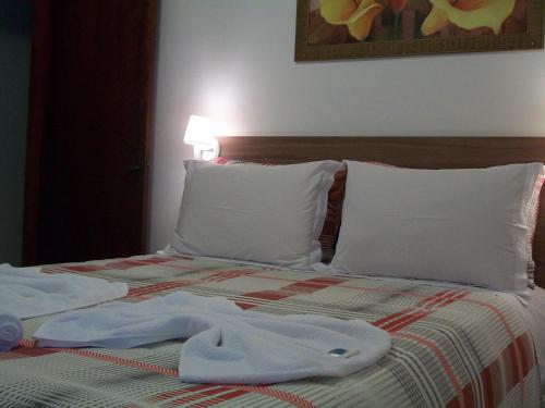 a bed with white pillows and towels on it at Hospedagem Da Laranjeira Gramado in Gramado