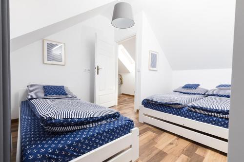 two beds in a bedroom with white walls and wood floors at Rodzinna Przystan in Uście