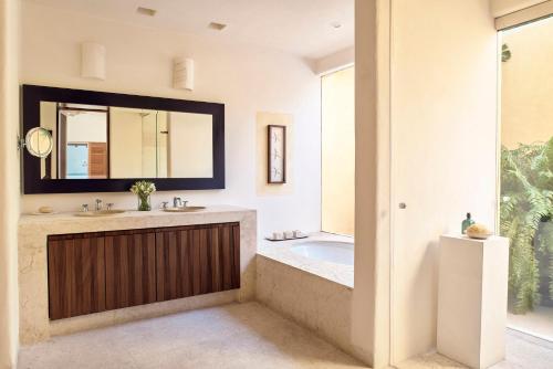 a bathroom with a tub and a sink and a mirror at Four Seasons Resort Punta Mita in Punta Mita