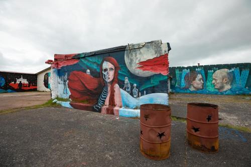 a wall with a painting on it with two barrels at Kleifar: Ocean View Apartment in Hellissandur
