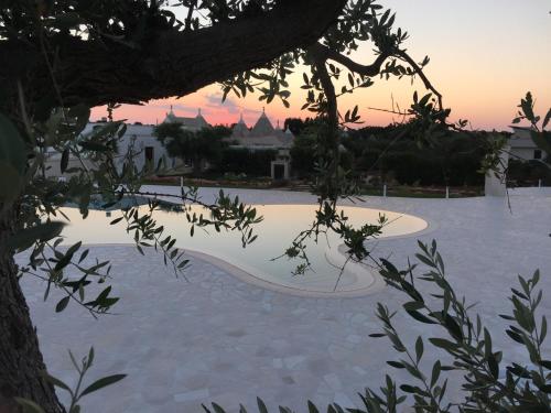a view of a pool with a sunset in the background at Trulli IsAgo in Locorotondo