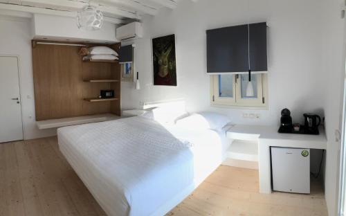sypialnia z białym łóżkiem i biurkiem w obiekcie Empress Villa w mieście Platis Gialos Mykonos