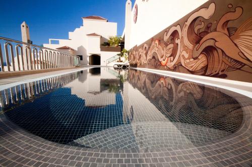 a swimming pool in front of a building with a mural at Royal Sun Resort in Acantilado de los Gigantes