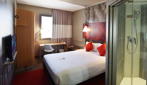a hotel room with a large bed and a shower at Ibis Sfax in Sfax