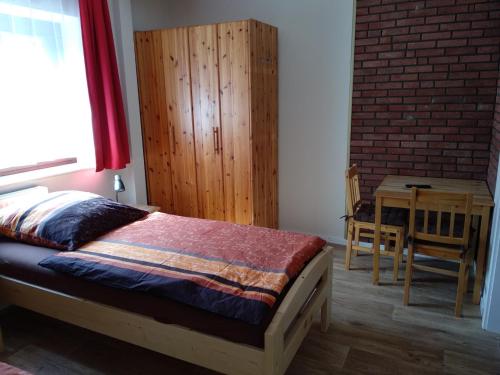 KirchlintelnにあるFerienhaus/ Monteurzimmer Luttumのベッドルーム1室(ベッド1台、木製キャビネット、テーブル付)