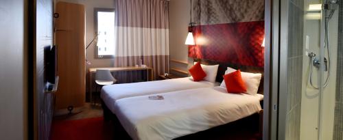 a hotel room with two beds with red pillows at Ibis Sfax in Sfax