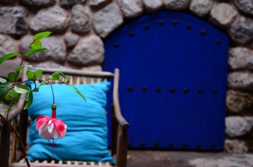 a blue pillow and a pink flower on a chair at Rumi Wasi in Cusco